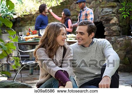 Stock Photograph - Smiling couple sitting together outdoors. Fotosearch
