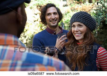 Smiling friends having wine outdoors View Large Photo Image Stock Photo - Smiling friends having wine outdoors. Fotosearch