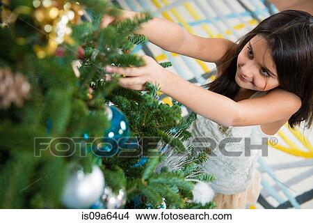 Picture - Smiling girl decorating Christmas tree. Fotosearch