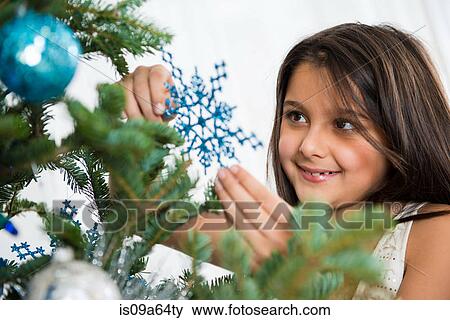 Stock Photo - Smiling girl decorating Christmas tree. Fotosearch