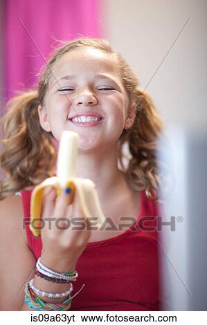 Stock Photograph - Smiling girl eating banana. Fotosearch