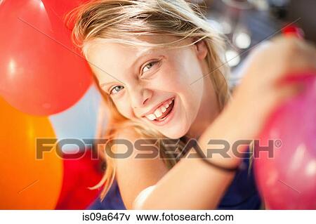 Stock Photo - Smiling girl holding balloon at party. Fotosearch