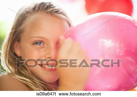 Stock Photograph - Smiling girl holding balloon at party. Fotosearch