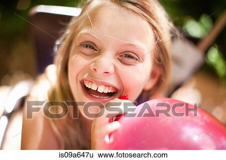 Smiling girl holding balloon at party View Large Photo Image Stock Photograph - Smiling girl holding balloon at party. Fotosearch