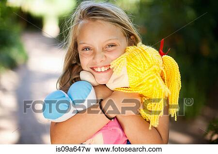 Smiling girl holding doll outdoors View Large Photo Image Stock Photo - Smiling girl holding doll outdoors. Fotosearch
