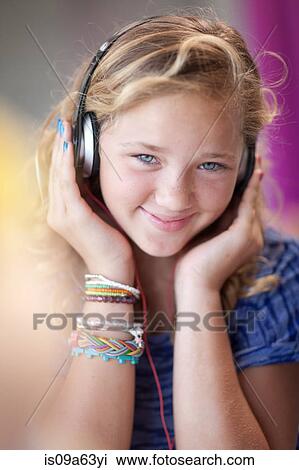 Stock Image - Smiling girl listening to headphones. Fotosearch