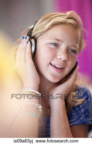 Stock Image - Smiling girl listening to headphones. Fotosearch