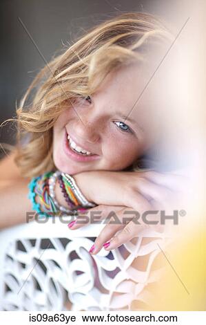 Stock Image - Smiling girl resting chin on bench. Fotosearch