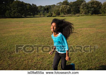 Stock Image - Smiling girl running in field. Fotosearch