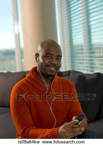 Smiling man listening to earphones View Large Photo Image Stock Photo - Smiling man listening to earphones. Fotosearch