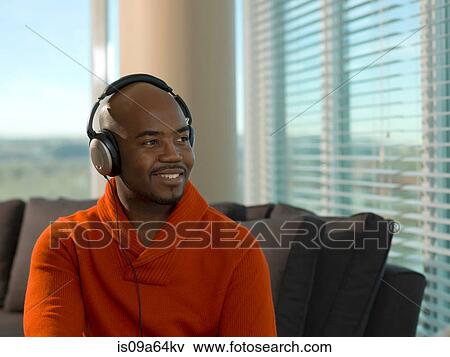 Stock Photo - Smiling man listening to headphones. Fotosearch