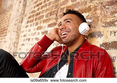 Stock Photo - Smiling man listening to headphones. Fotosearch
