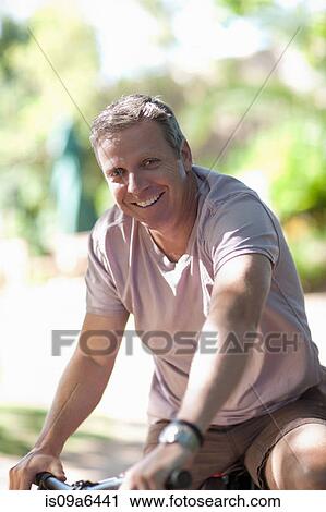 Stock Image - Smiling man riding mountain bike. Fotosearch