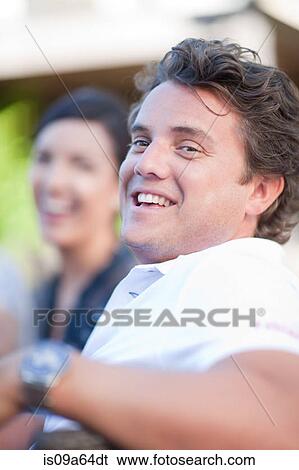 Stock Photograph - Smiling man sitting at table outdoors. Fotosearch