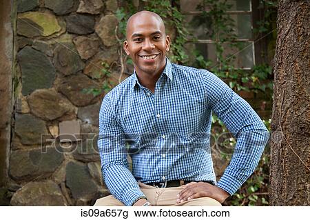 Stock Image - Smiling man sitting outdoors. Fotosearch