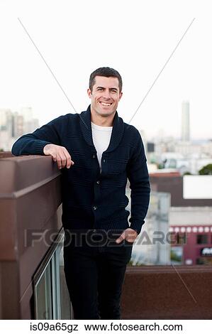 Smiling man standing on urban balcony View Large Photo Image Stock Photo - Smiling man standing on urban balcony. Fotosearch