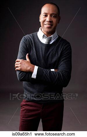 Stock Image - Smiling man standing with arms crossed. Fotosearch