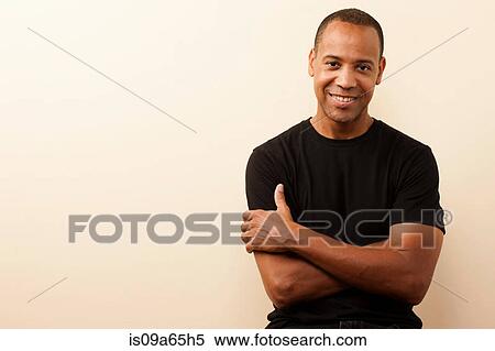 Stock Photography - Smiling man standing with arms crossed. Fotosearch