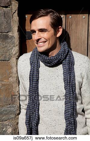 Stock Image - Smiling man wearing scarf outdoors. Fotosearch
