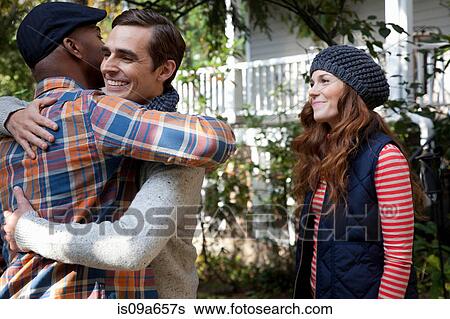 Stock Photograph - Smiling men hugging outdoors. Fotosearch