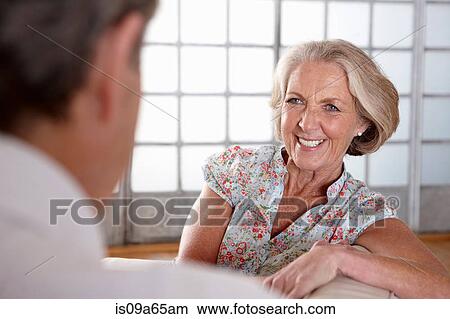 Smiling older couple talking on sofa View Large Photo Image Picture - Smiling older couple talking on sofa. Fotosearch