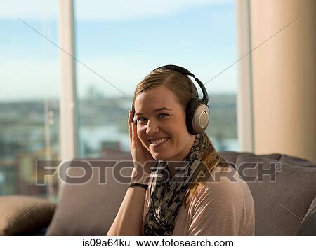 Stock Photograph - Smiling woman listening to headphones. Fotosearch