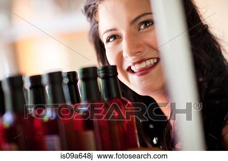 Stock Image - Smiling woman shopping for vinegar. Fotosearch