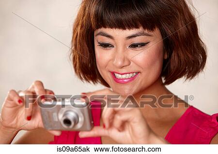 Stock Image - Smiling woman taking pictures. Fotosearch