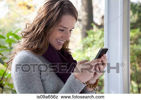Smiling woman using cell phone View Large Photo Image Stock Photo - Smiling woman using cell phone. Fotosearch