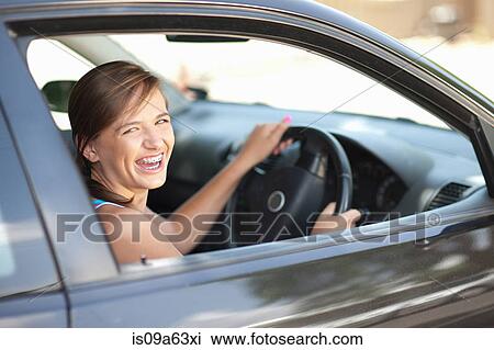 Stock Image - Teenage girl in braces driving car. Fotosearch