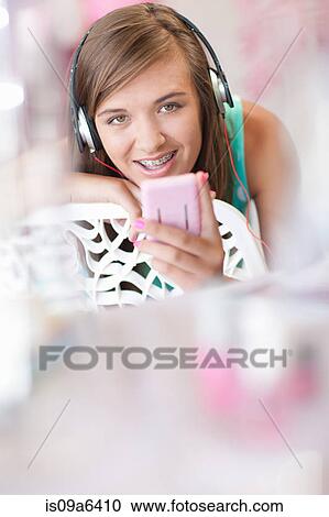 Stock Image - Teenage girl listening to headphones. Fotosearch