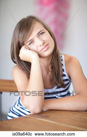 Stock Image - Teenage girl resting cheek on hand. Fotosearch