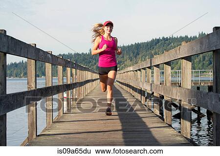 Stock Photograph - Teenage girl running on wooden dock. Fotosearch