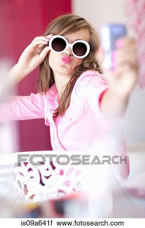 Stock Image - Teenage girl taking picture of herself. Fotosearch