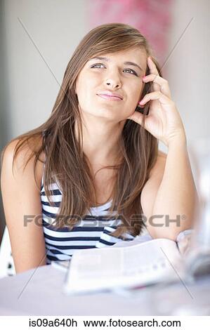 Stock Image - Teenage girl thinking at desk. Fotosearch
