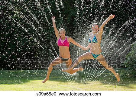 Teenage girls playing in sprinkler View Large Photo Image Stock Image - Teenage girls playing in sprinkler. Fotosearch