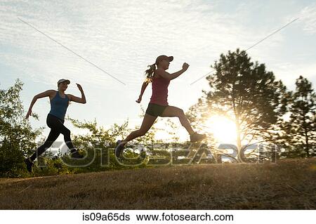 Stock Photograph - Teenage girls running together in field. Fotosearch