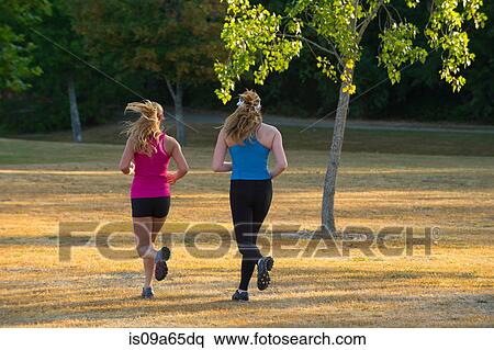 Stock Photography - Teenage girls running together in field. Fotosearch