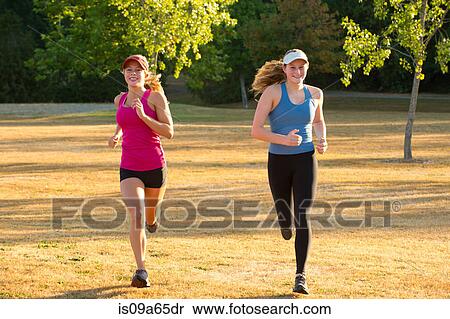 Stock Photography - Teenage girls running together in field. Fotosearch