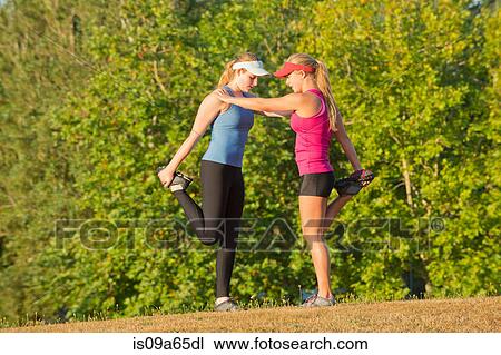 Stock Image - Teenage girls stretching in field. Fotosearch