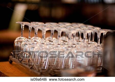 Stock Image - Upturned wine glasses in rack. Fotosearch