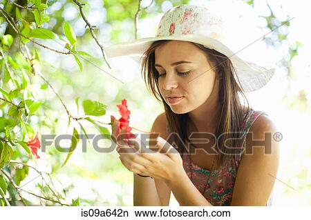Picture - Woman admiring flower in park. Fotosearch