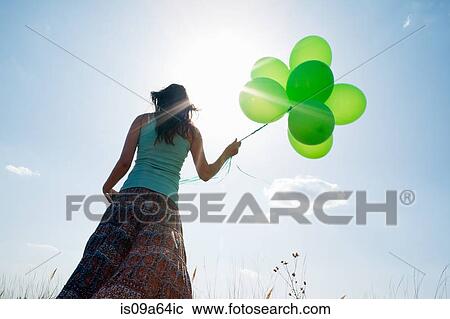 Stock Image - Woman carrying bunch of balloons. Fotosearch