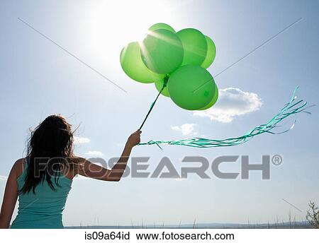 Stock Image - Woman carrying bunch of balloons. Fotosearch