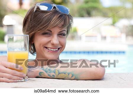Stock Image - Woman drinking juice at edge of pool. Fotosearch