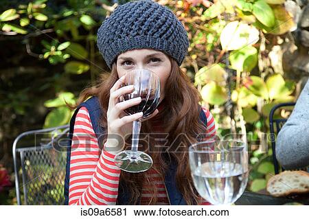 Stock Image - Woman drinking wine at table outdoors. Fotosearch
