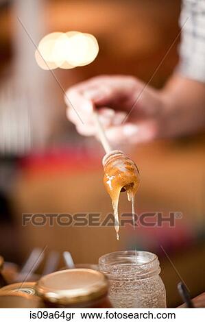 Stock Photography - Woman examining honey in grocery. Fotosearch