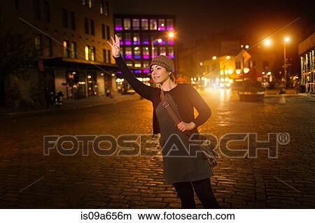 Woman hailing taxi on city street View Large Photo Image Picture - Woman hailing taxi on city street. Fotosearch