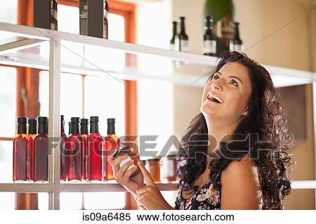 Stock Photography - Woman holding jam jar in grocery. Fotosearch