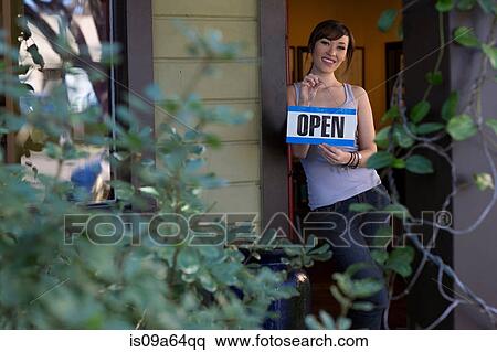 Woman holding open sign in store View Large Photo Image Stock Photography - Woman holding open sign in store. Fotosearch